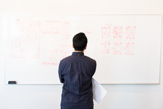 Technology leader reviewing architecture diagrams on whiteboard