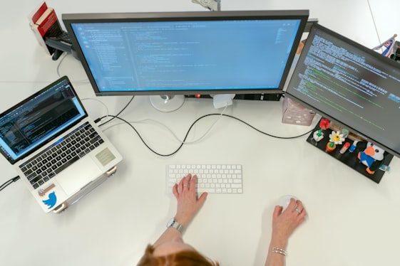 Software developer coding at multi-monitor workstation
